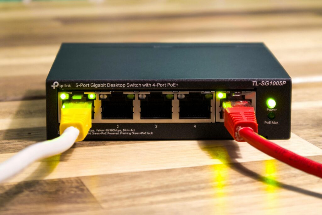 Close-up of a TP-Link Ethernet switch with yellow, red, and white cables connected.